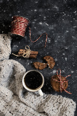 Winter composition. Cup of coffee, cookie, lights on a dark background. Flat lay