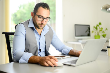 portrait of handsome trendy casual mid age business man in office desk with laptop computer