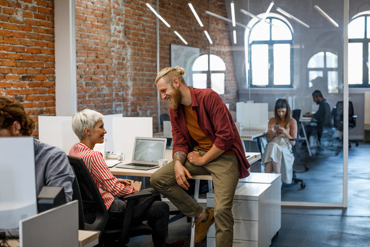 Handsome blonde businessman chatting with pretty businesswoman at work.