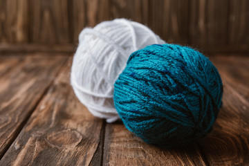 close up view of white and blue yarn balls on wooden tabletop