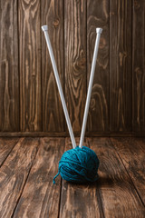 close up view of blue yarn ball and knitting needles on wooden tabletop