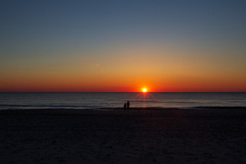 Fototapeta na wymiar Mutter mit Kind schauen den Sonnenuntergang am Meer