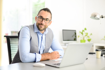 portrait of handsome trendy casual mid age business man in office desk with laptop computer