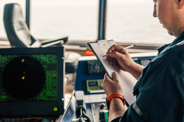 Marine navigational officer or chief mate on navigation watch on ship or vessel. He fills up...