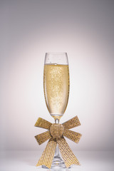 close up view of glass of champagne with ribbon on grey backdrop