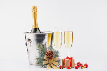 close up view of bottle of champagne in bucket, glasses of champagne and wrapped christmas gift on grey background