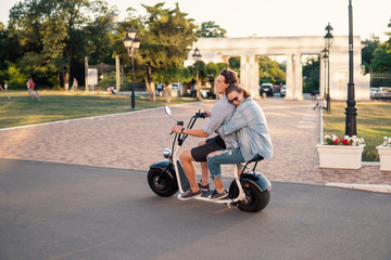 Lovely young couple driving electric bike. Modern city transportation