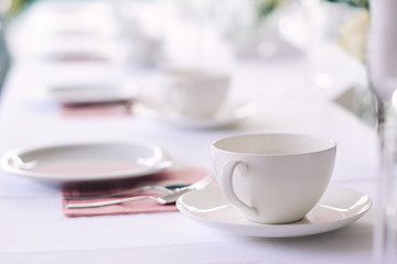 Weißes Geschirr gedeckt auf weißer Tischdecke mit rosaroten Servietten