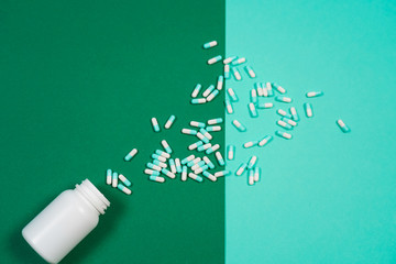 Pharmaceutical medicine pills, capsules and bottle on colored background.