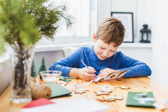 Adorable boy preparing christmas cards for grandparents.