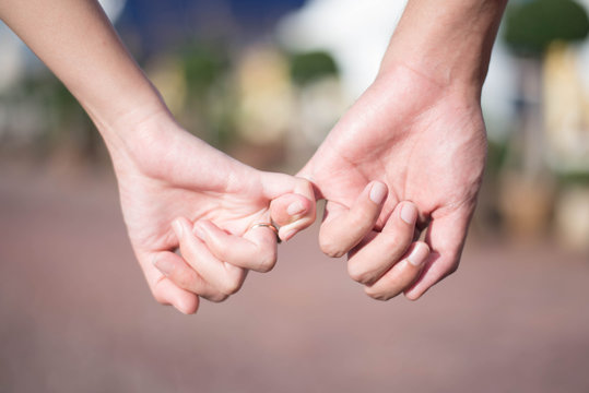 Woman & man hook little finger for holding hands