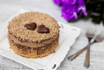 delicious sweet cake on wooden background with purple flowers flatlay