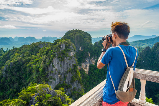 Young traveler takes a photo of mountains covered with the jungle from the Tiger Cave Mountain Temple in Krabi, Thailand.