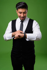 Young bearded Iranian businessman against green background