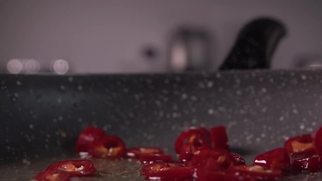 Chopped chili pepper being dropped into a frying pan in slow motion, 240 fps