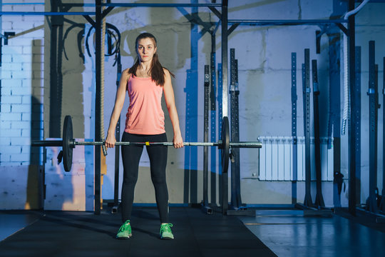Athletic woman exercising with a barbell in the gym