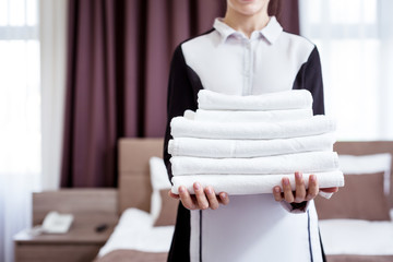 Absolutely clean. Selective focus of clean white towels being held by a hotel maid