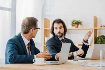 two adult men sitting at table and talking in insurance office