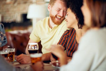 Friends chatting and drinking alcohol while  sitting at restaurant. Multi ethnic group.