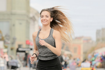 Smiling girl running on city street.