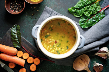 Slow cooking soup with curry, chickpeas, beans and chard. The concept of autumn or winter food