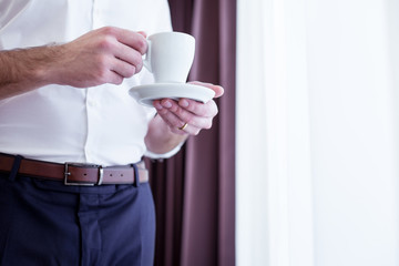 Coffee break. Coffee cup in hands of a nice successful businessman while having a break from work
