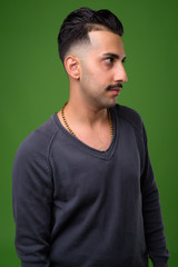 Young handsome Iranian man with mustache against green backgroun