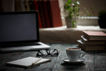 A cup of coffee in the workplace on a wooden table.