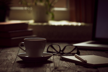 A cup of coffee in the workplace on a wooden table.