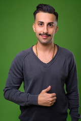 Young handsome Iranian man with mustache against green backgroun