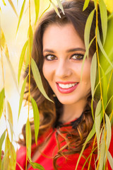 Fototapeta premium Beautiful young woman in red dress on a sunny autumn day