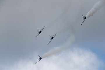 Low angle view of airshow in cloudy sky