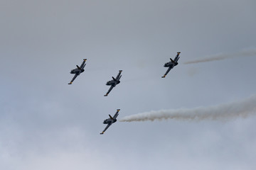 Low angle view of airshow in cloudy sky