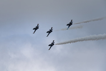 Low angle view of airshow in cloudy sky