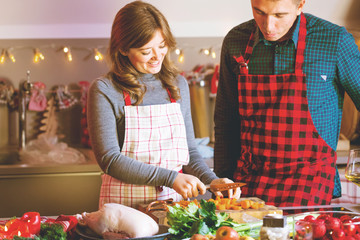 Couple celebrating Christmas in the kitchen cooking christmas duck or Goose