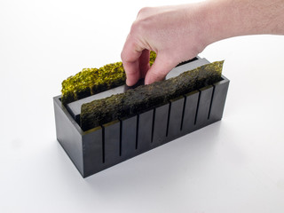 apretando con un apretador el arroz de un sushi en el interior de un molde de corte