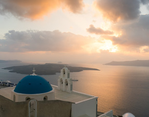 Fototapeta na wymiar sunset over aegean sea with view to Virgin Mary Catholic Church Three Bells of Fira, Santorini.