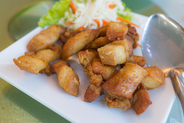 Fried Streaky Pork in white dish on glass table background,