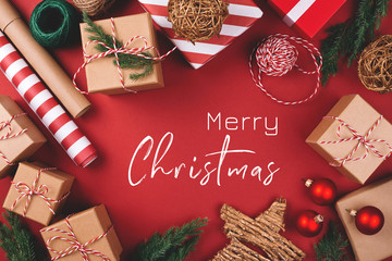 Christmas greeting card. Background with gift boxes, clews of rope, paper's rools and decorations on red. Preparation for holidays. Top view.