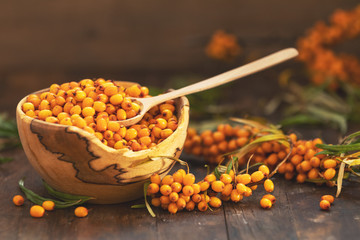 Natural, organic sea buckthorn berry in bowl on dark wooden background