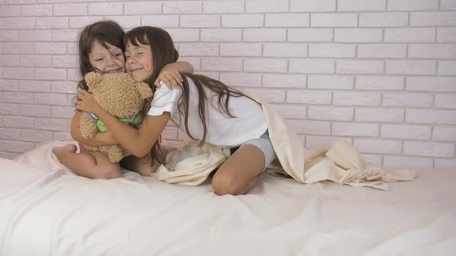 Happy sisters play in the bedroom.
