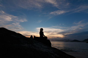 mulher meditando na praia, no pôr do sol