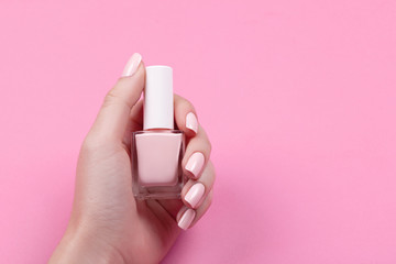 girl holds nail polish with a beautiful manicure