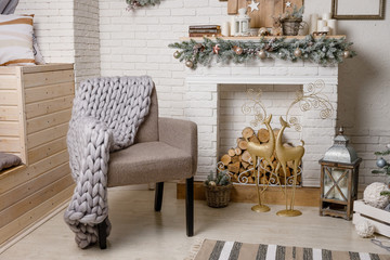 The Scandinavian style Christmas or New Year background: Christmas tree by the fireplace, pink glass balls and toys, wooden decoration, wool blanket, floor lamp