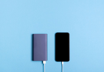 Smartphone charging with power bank on blue background