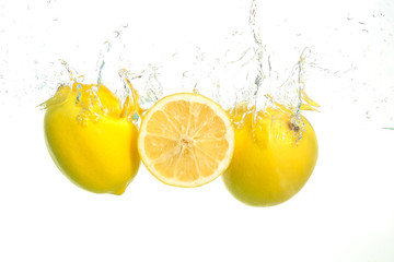 Three lemons spash in water on white