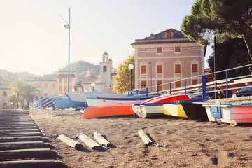 Beautiful beach with yellow sand and colorful boats in old Italian town Sestri Levante (Liguria) on sunset.