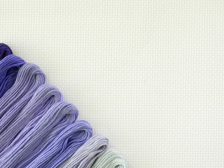multi-colored embroidery floss on white canvas. copy space