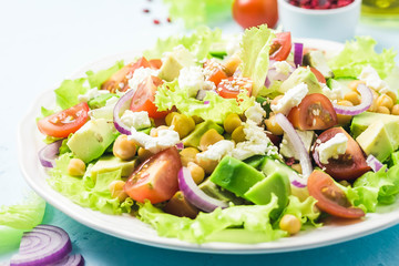 Garbanzo beans avocado cherry tomato feta cheese salad with lemon dressing. Selective focus, space for text.