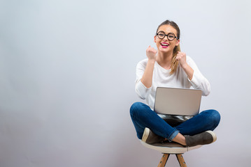 Young woman with a laptop computer with successful pose on a gray background